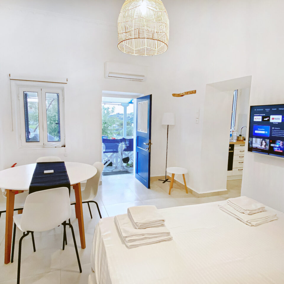 Living room with covertible sofa bed, air conditioner, TV, dining table and access to the front yard, in Kini Syros